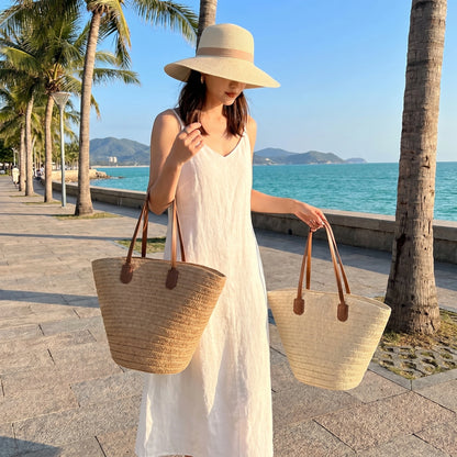 Model showcases the Womens Woven Summer Tote in a outfit, showing a light and airy color palette against a beachy backdrop.