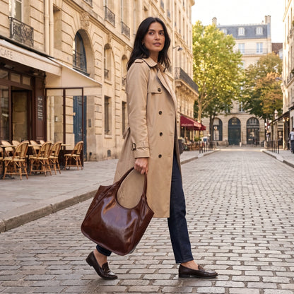 A model showcases the glossy cowhide Roma Tote Bag in outfit, showing neutral tones against minimalist backdrop. — view 2