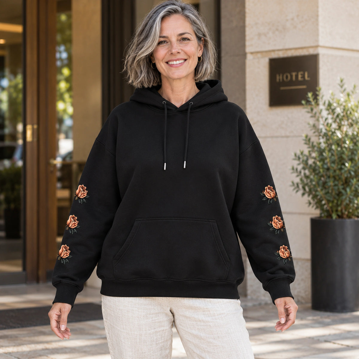 Black butterfly and rose print hoodie, complete front view on a mature model — view 5