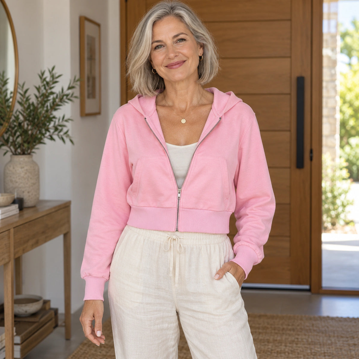 Pink Alina cropped zip up hoodie, partially open zipper view on mature model at home — view 6
