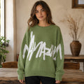 Woman wearing green graffiti jacquard letterman sweater, complete front view