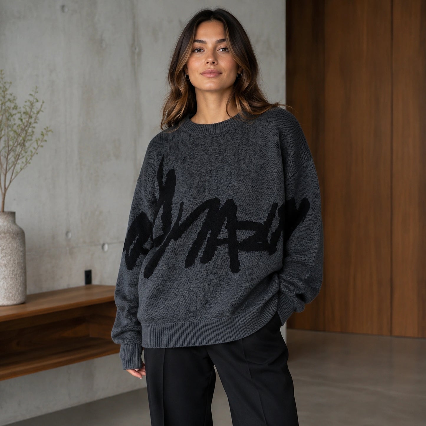 Woman wearing dark gray graffiti jacquard letterman sweater, complete front view — view 3