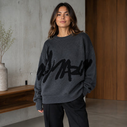 Woman wearing dark gray graffiti jacquard letterman sweater, complete front view — view 3