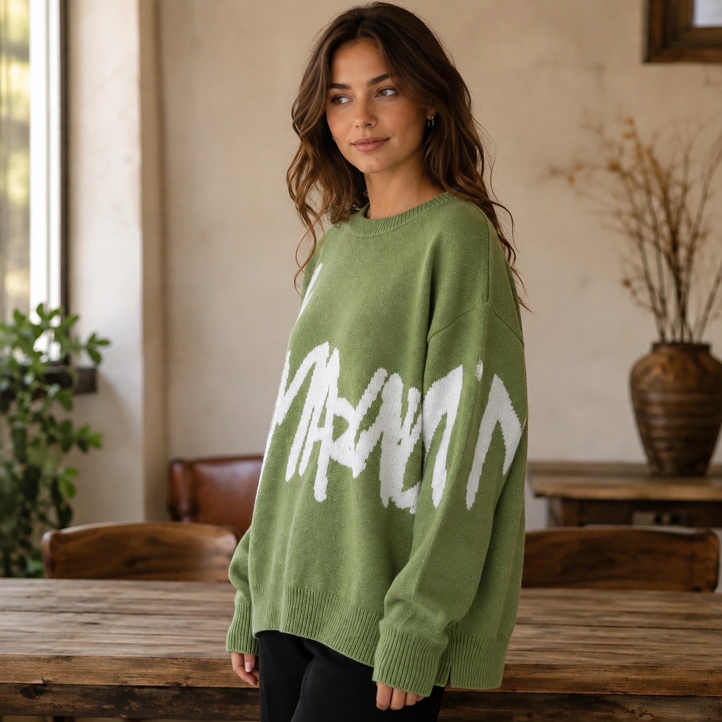 Woman wearing green graffiti jacquard letterman sweater, side view — view 6