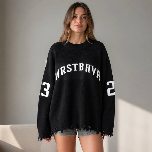 Woman wearing black oversized jacquard letterman sweater, complete front view — view 2