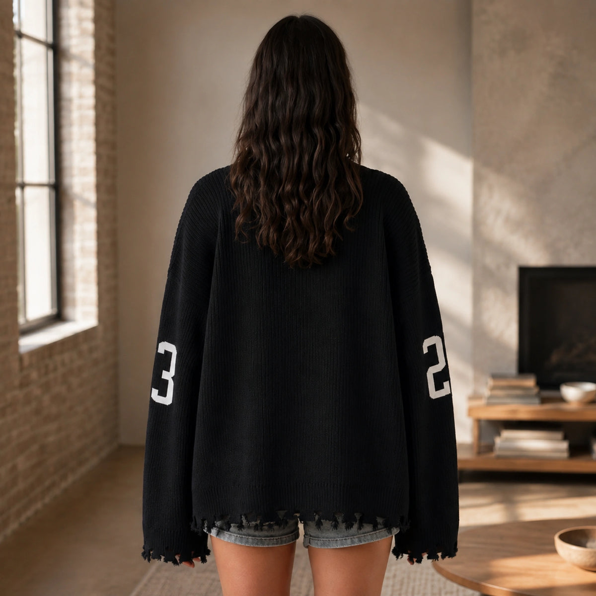 Woman wearing black oversized jacquard letterman sweater, true back view — view 6