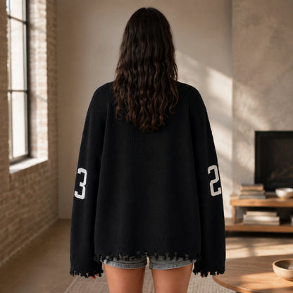 Woman wearing black oversized jacquard letterman sweater, true back view — view 6