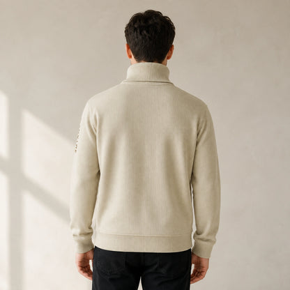 Male model wearing men's beige embroidered turtleneck letterman sweater, complete rear view — view 3