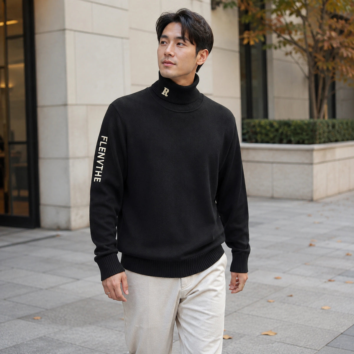 Male model wearing black embroidered turtleneck letterman sweater in a modern winter city setting — view 6