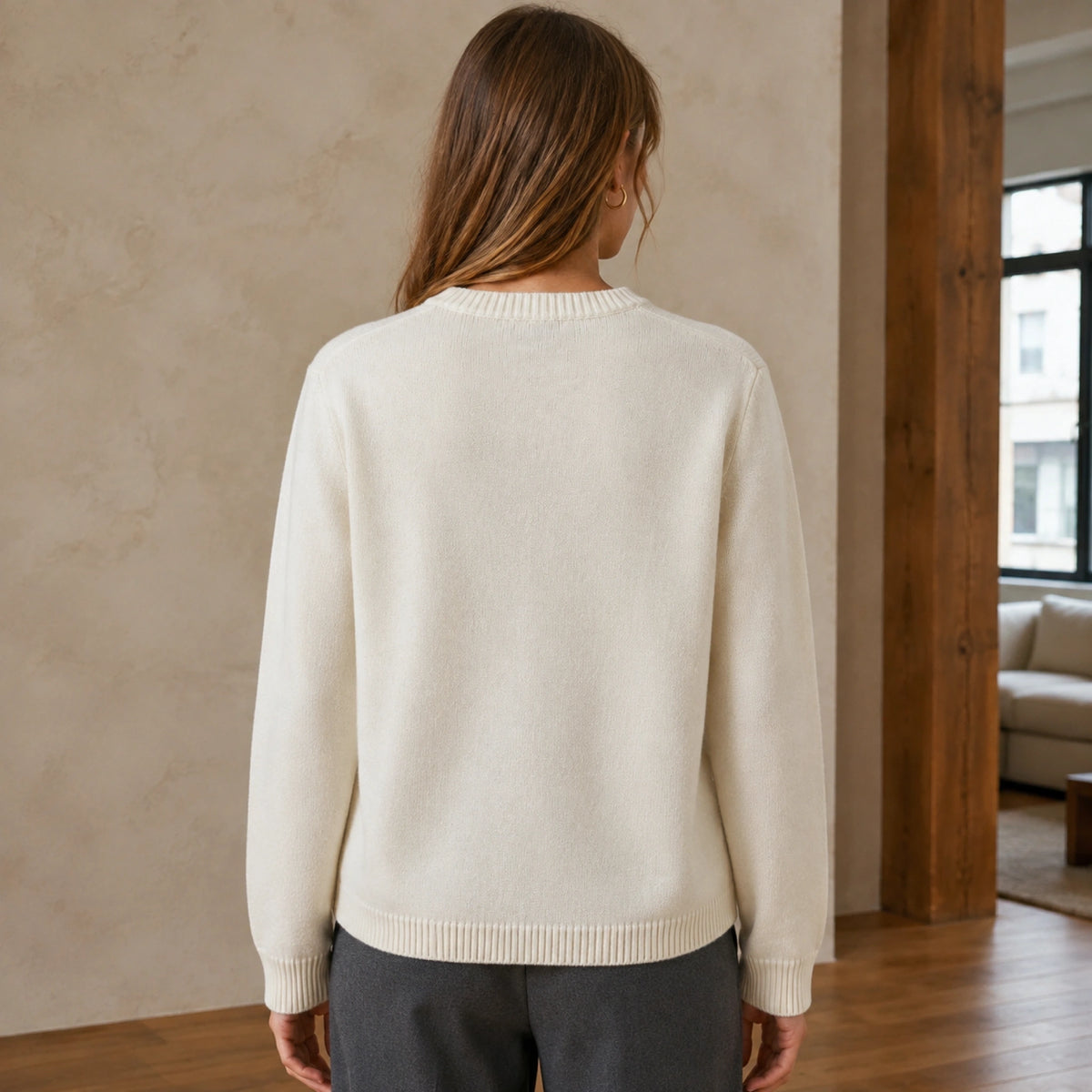 Female model wearing women's light beige cursive jacquard letterman sweater, complete rear view — view 2