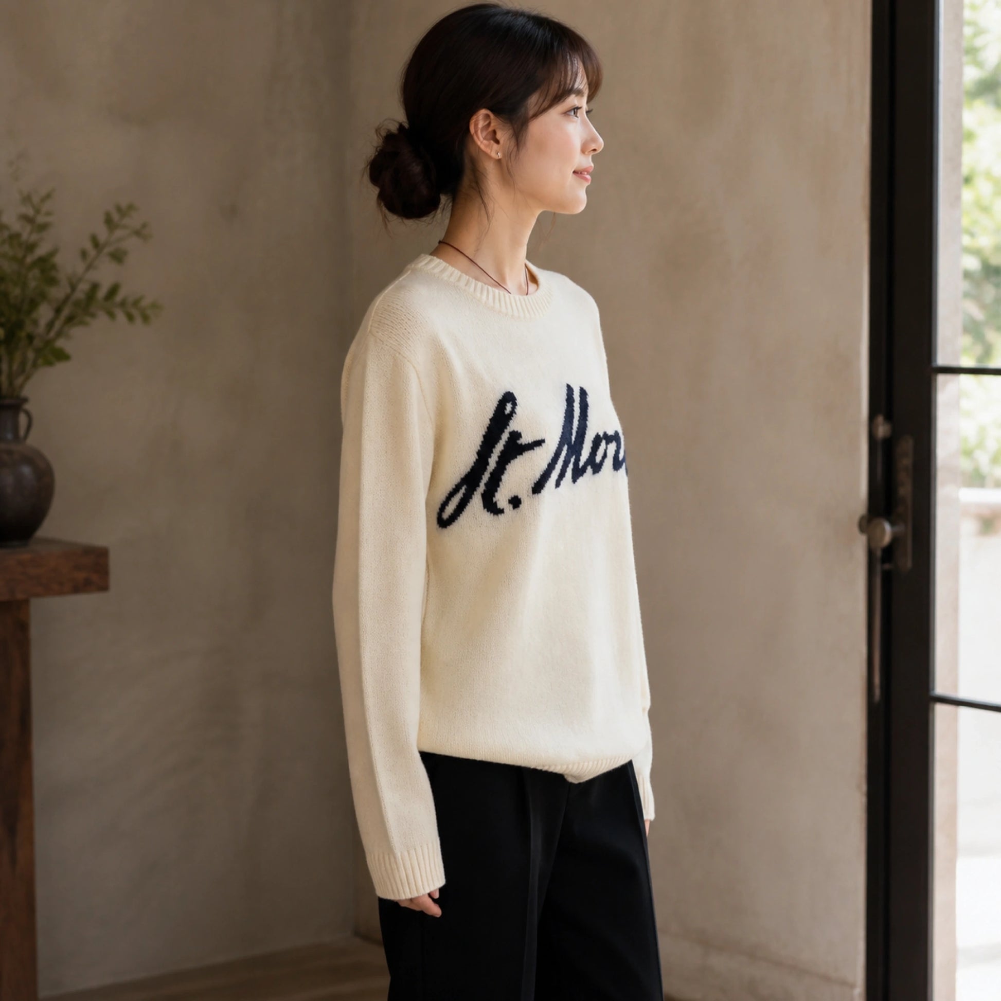 Female model wearing women's light beige cursive jacquard letterman sweater, complete side view — view 4