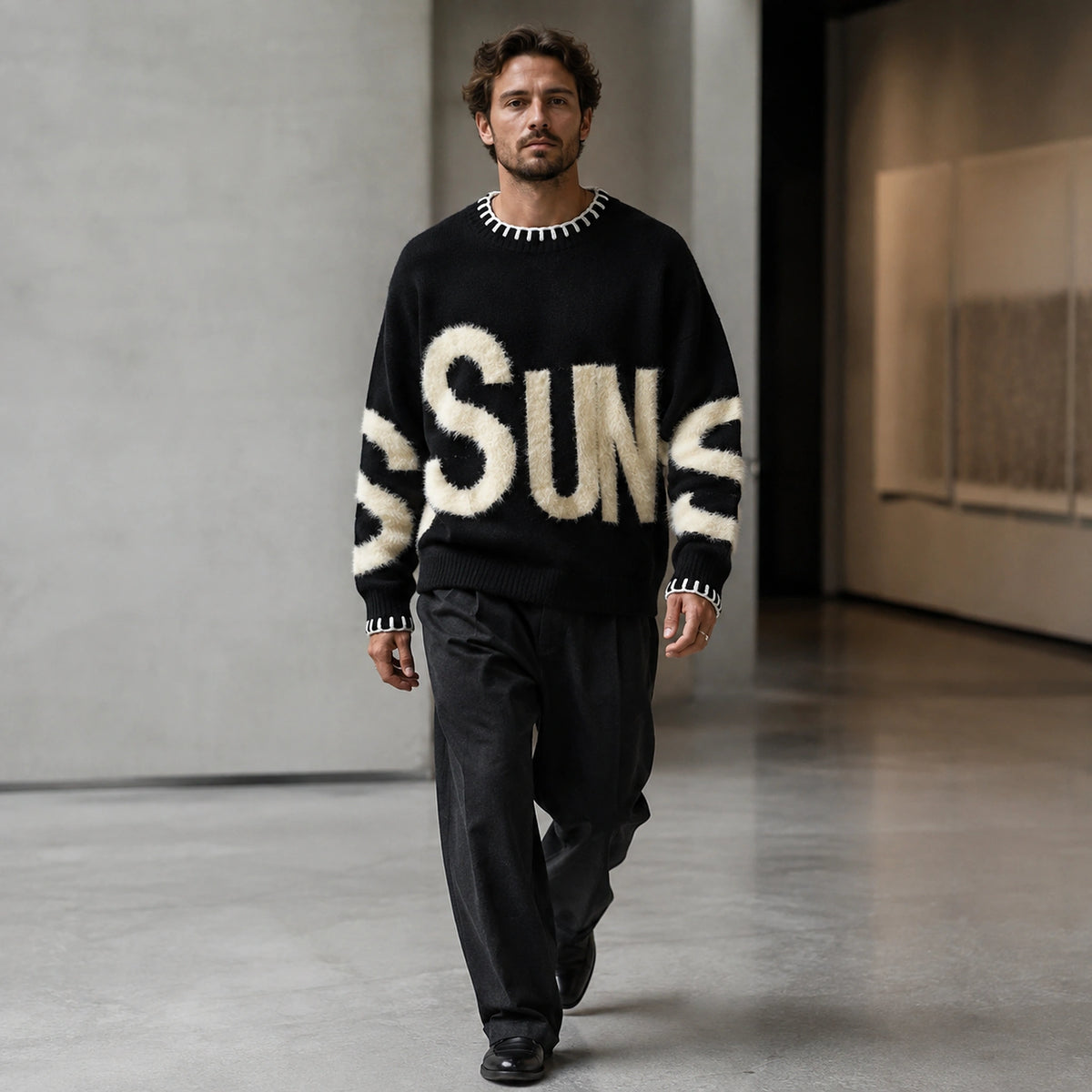 Man wearing black fuzzy letter pattern letterman sweater, complete front view — view 4