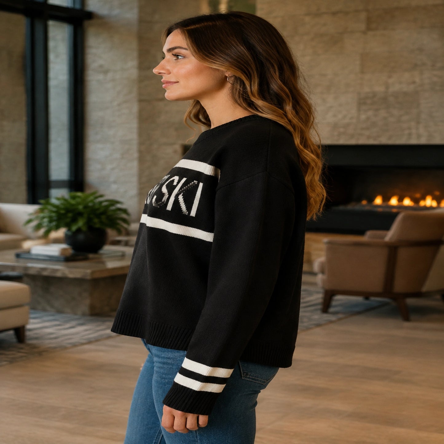 Female model wearing women's black après ski jacquard letterman sweater, complete side view — view 6