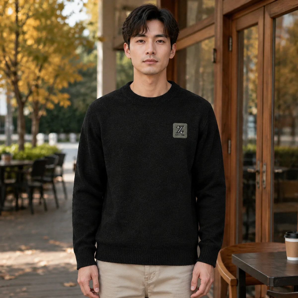 Male model wearing men's black fleece lined patch letterman sweater, complete front view — view 3