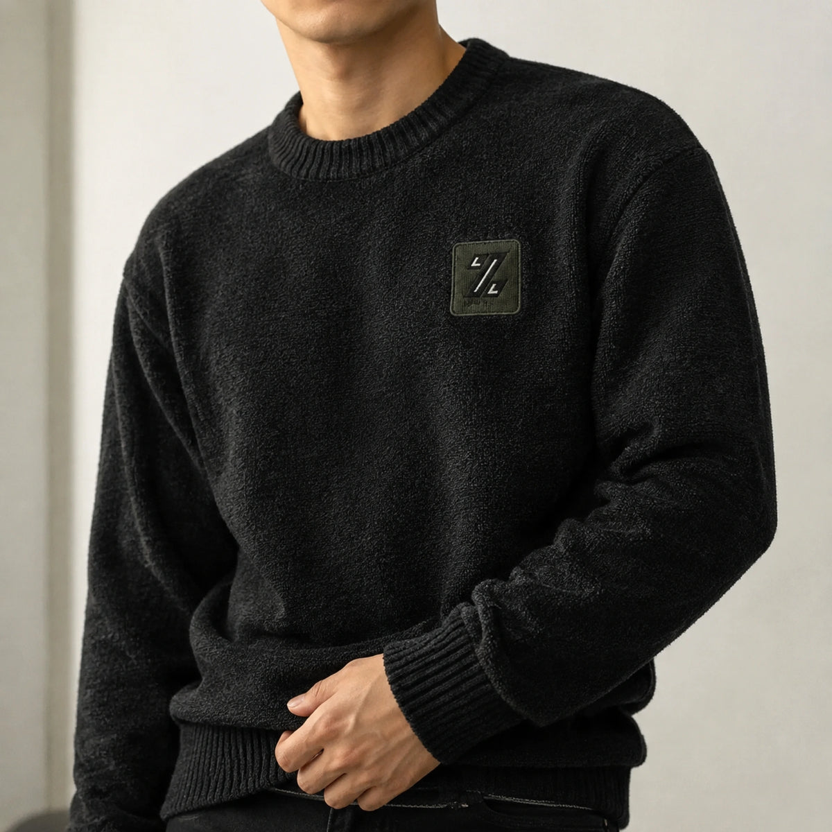 Male model wearing black fleece lined patch letterman sweater, close up neckline and texture detail — view 6