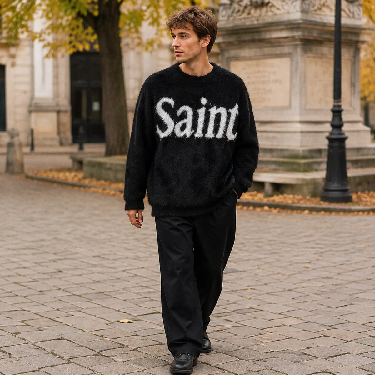 Male model wearing black fuzzy script letterman sweater in an autumn city setting — view 5