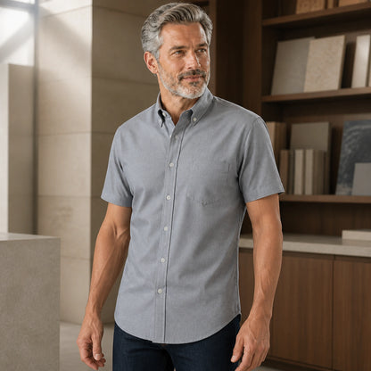 Side three quarter view of a mature man wearing the gray Oxford shirt, showing sleeve, pocket, seam and hem — view 9