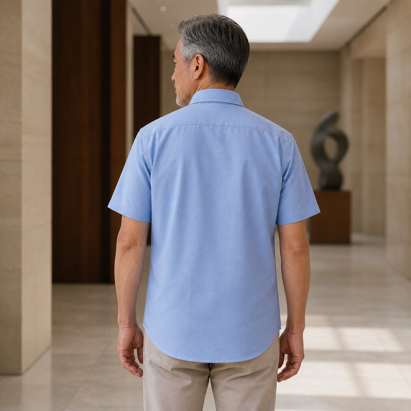 Mature man wearing Blue classic fit short sleeve Oxford shirt, realistic rear view showing collar, yoke, sleeves — view 9