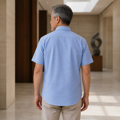Mature man wearing Blue classic fit short sleeve Oxford shirt, realistic rear view showing collar, yoke, sleeves — view 9