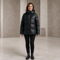 parka coat — Woman wearing glossy black hooded puffer coat, complete front view