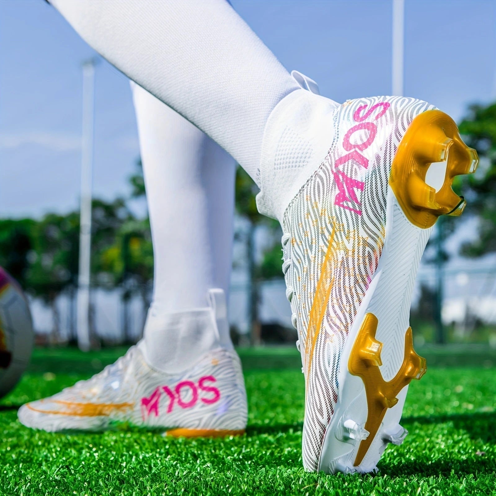 White soccer cleats with gold and pink accents on green grass field — view 16 — view 16
