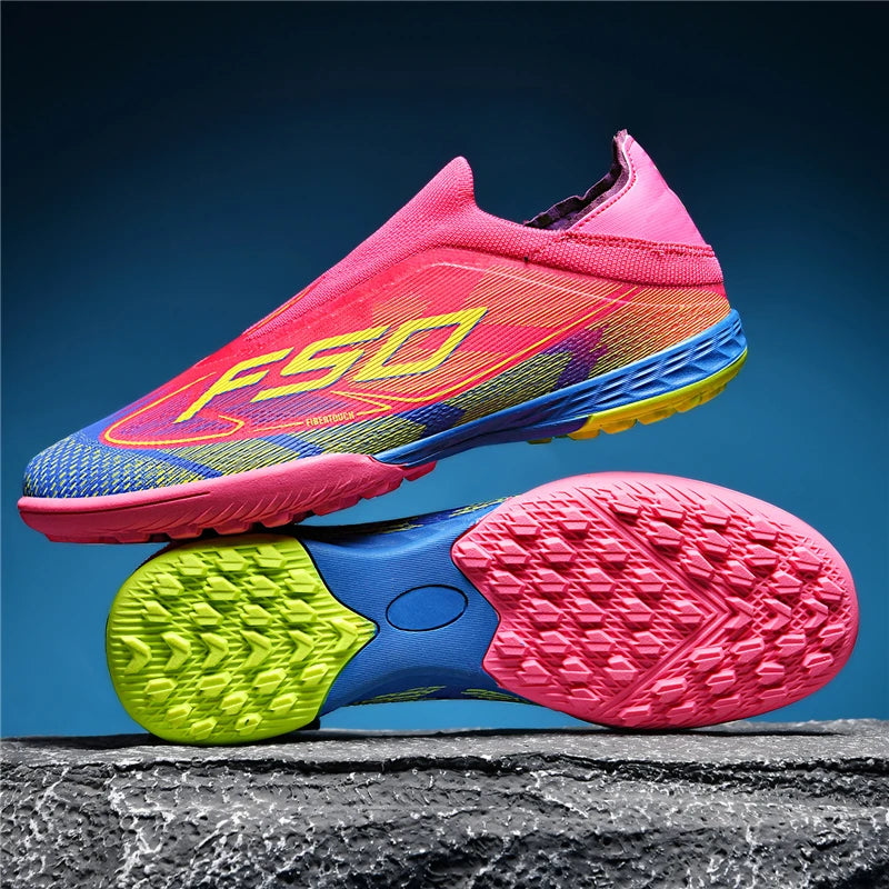 Bright pink and blue soccer cleats with non slip soles, displayed against a textured surface — view 2 — view 4
