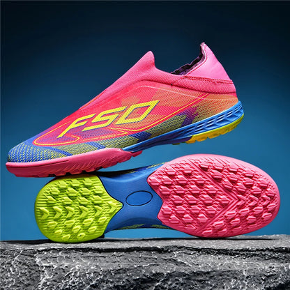 Bright pink and blue soccer cleats with non slip soles, displayed against a textured surface — view 2 — view 4