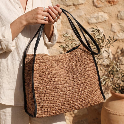 A model showcases the Versatile Everyday Tote Bag in, casual outfit showing light colored blouse and high waisted jeans