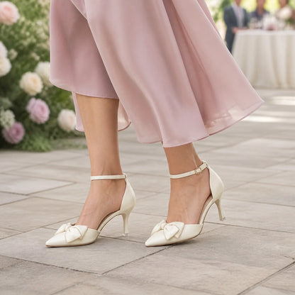 Mature woman wearing ivory bow detail wedding guest shoes outdoors — view 7